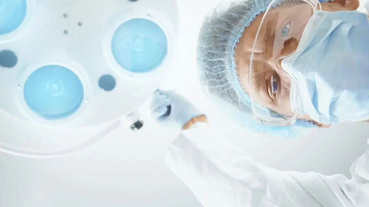 Chirurg w masce i okularach pochyla się nad pacjentem, przygotowując zalecenia po operacji prostaty.