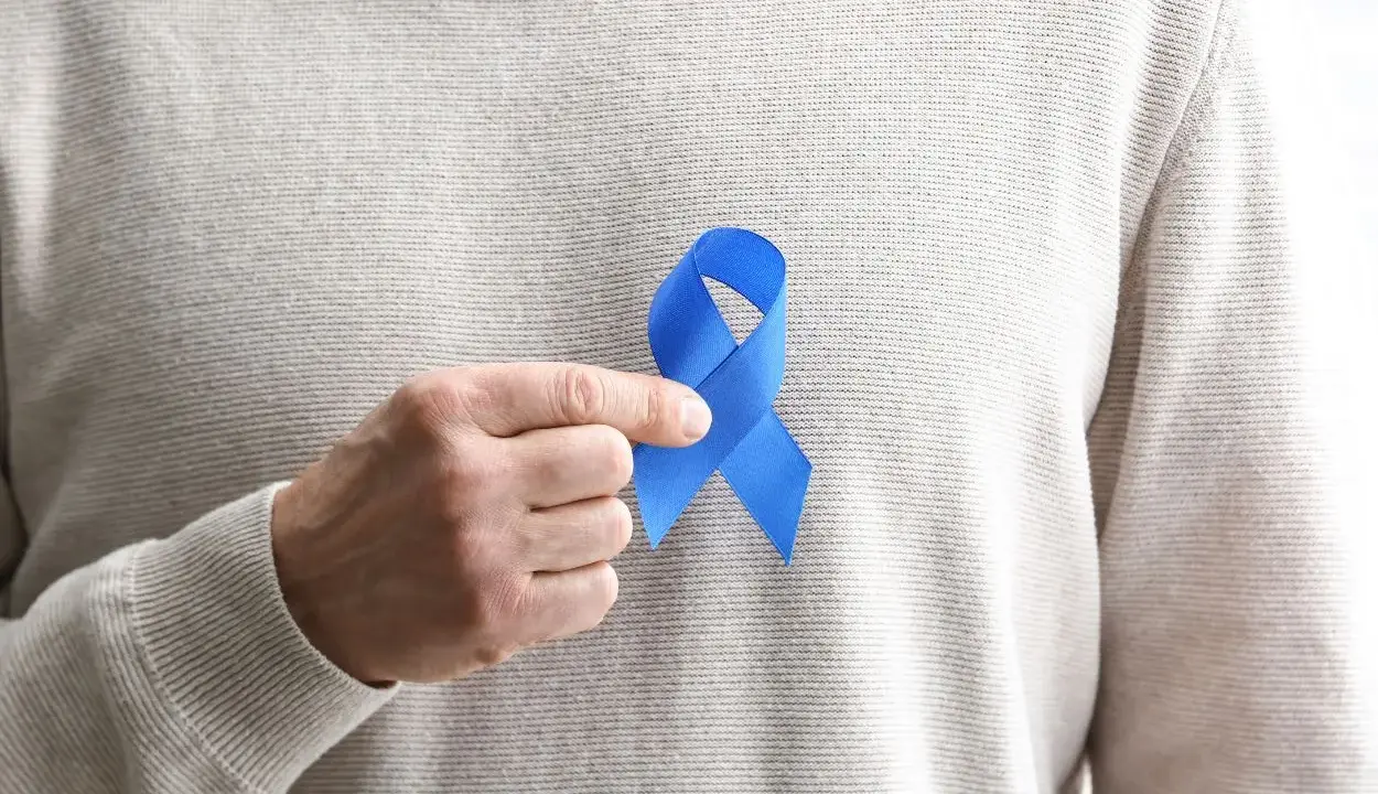 Mężczyzna trzyma niebieską wstążkę symbolizującą świadomość raka prostaty. Rozważamy usunięcie prostaty skutki.