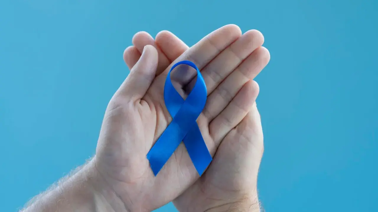 Dłonie trzymające niebieską wstążkę symbolizującą wsparcie dla mężczyzn. Warto poznać domowe sposoby na prostatę.
