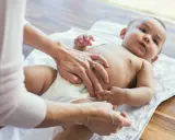 Mama sprawdza brzuszek maluszka, martwiąc się, że dziecko nie sika od 24 godzin.