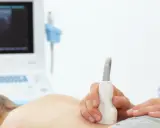 Badanie USG nerek u dziecka, które może pomóc zdiagnozować zapalenie nerek. Lekarz przykłada sondę do pleców pacjenta.