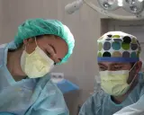 Chirurdzy w maskach i czepkach analizują sytuację po laserowym usunięciu prostaty, rozważając potencjalne powikłania.