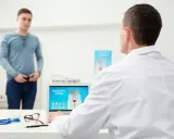Lekarz omawia z pacjentem problemy z zatrzymaniem moczu po operacji prostaty, analizując na ekranie laptopa układ moczowo-płciowy.