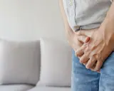 Mężczyzna trzymający się za krocze, sugerujące problem z żylakami powrózka nasiennego. Rozważ tabletki na żylaki powrózka nasiennego.