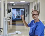 Lekarz w niebieskiej koszuli wskazuje na ekranie komputerowym obraz z badania, które może być związane z biopsją fuzyjną prostaty.