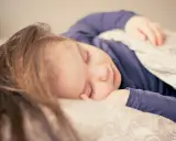 Dziecko śpi spokojnie, choć czasem **moczenie nocne na tle nerwowym** może zakłócać sen.