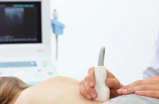 Badanie USG nerek u dziecka, które może pomóc zdiagnozować zapalenie nerek. Lekarz przykłada sondę do pleców pacjenta.